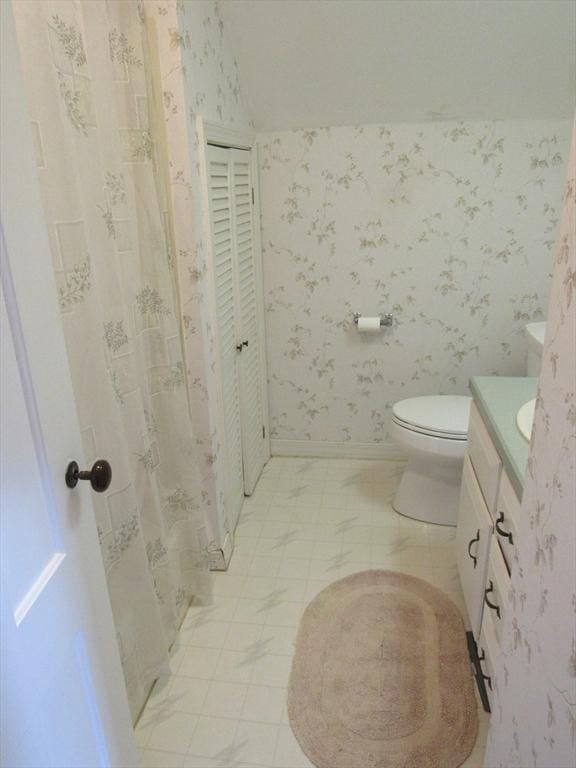 full bathroom featuring vanity, baseboards, wallpapered walls, tile patterned floors, and toilet