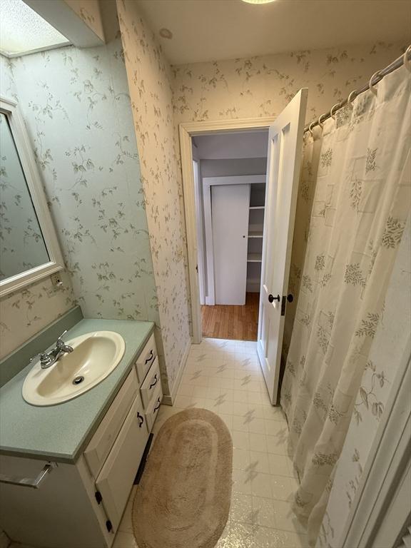 bathroom featuring wallpapered walls, tile patterned floors, vanity, and baseboards