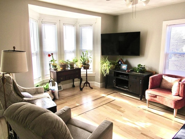 living room featuring baseboards, light wood-style floors, and a ceiling fan