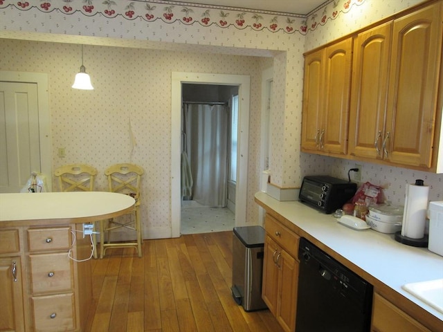 kitchen with wallpapered walls, decorative light fixtures, light countertops, black dishwasher, and light wood-style flooring