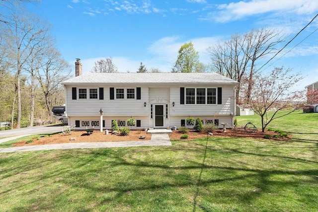 bi-level home featuring a chimney and a front lawn