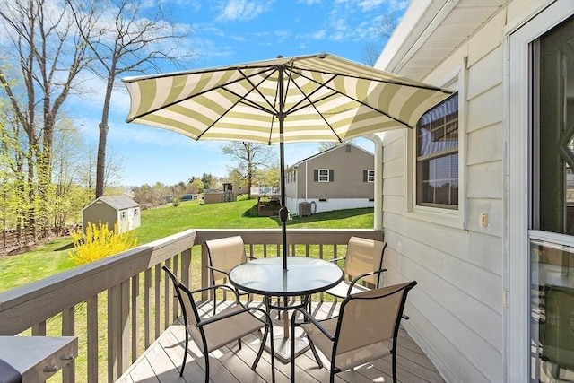 wooden deck featuring a storage shed, an outbuilding, a lawn, and outdoor dining space