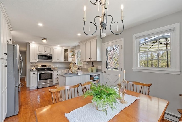 dining space with a baseboard radiator, recessed lighting, light wood-style flooring, and a notable chandelier
