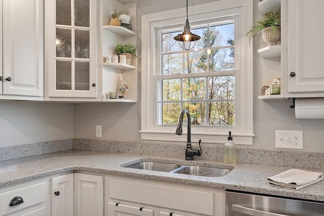 kitchen featuring stainless steel dishwasher, open shelves, a sink, and white cabinets