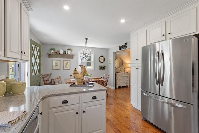 kitchen with light wood-type flooring, light stone counters, white cabinets, a peninsula, and stainless steel appliances