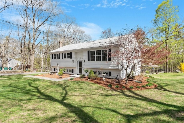 rear view of house featuring a chimney and a yard