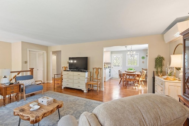 living area with an inviting chandelier, a wall mounted AC, and wood finished floors