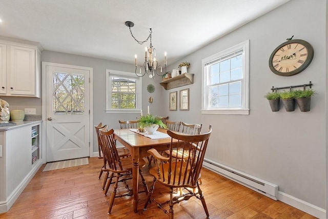 dining area featuring baseboards, an inviting chandelier, baseboard heating, and light wood-style floors