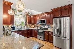 5 Comanche Cir Unit 5, Haverhill, MA 01835 - kitchen featuring stainless steel appliances, tasteful backsplash, light stone counters, a chandelier, and a sink