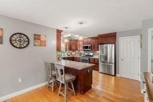 5 Comanche Cir Unit 5, Haverhill, MA 01835 - kitchen featuring stainless steel appliances, a peninsula, a kitchen bar, light wood-style floors, and hanging light fixtures