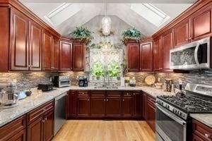 5 Comanche Cir Unit 5, Haverhill, MA 01835 - kitchen featuring stainless steel appliances, a skylight, light wood-style floors, tasteful backsplash, and vaulted ceiling