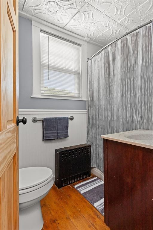 85 Flint St, Salem, MA 01970 - full bathroom with radiator, an ornate ceiling, vanity, wood finished floors, and a shower with shower curtain