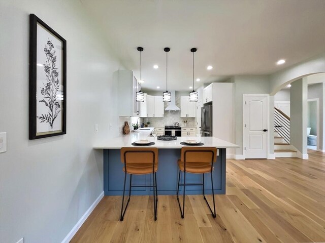 101 N Rd, Westfield, MA 01085 - kitchen featuring appliances with stainless steel finishes, a peninsula, wall chimney exhaust hood, light wood-style floors, and light countertops