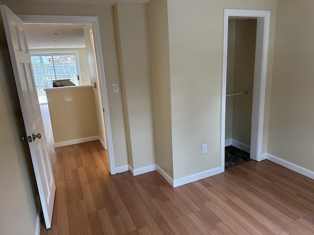 hall with light wood-style flooring and baseboards