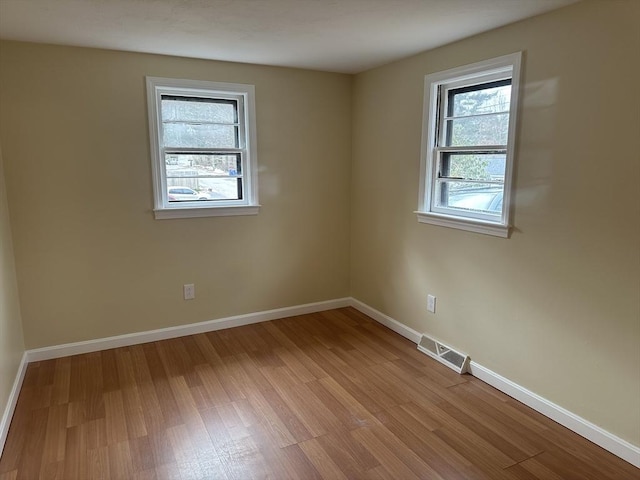 unfurnished room featuring baseboards, visible vents, and light wood-style flooring