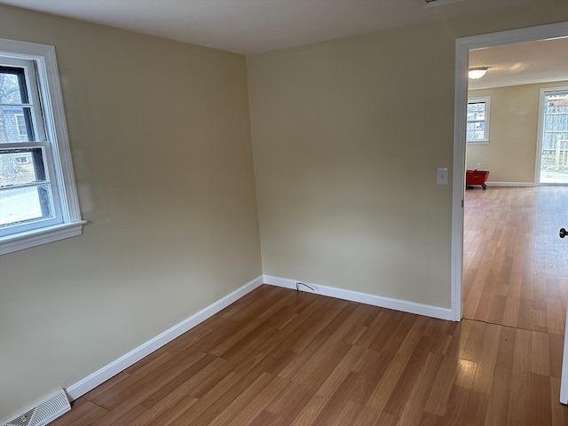 spare room with visible vents, baseboards, and wood finished floors