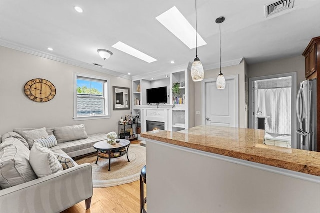 10 Mitchell St Unit 3, Boston, MA 02127 - living area featuring ornamental molding, light wood-type flooring, a skylight, a warm lit fireplace, and recessed lighting