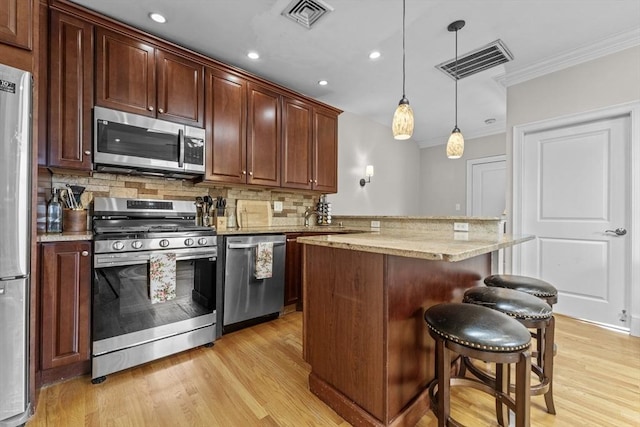 10 Mitchell St Unit 3, Boston, MA 02127 - kitchen featuring stainless steel appliances, ornamental molding, decorative backsplash, light wood finished floors, and a kitchen breakfast bar