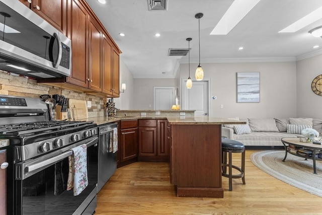 10 Mitchell St Unit 3, Boston, MA 02127 - kitchen featuring appliances with stainless steel finishes, light wood-style floors, a peninsula, a kitchen breakfast bar, and crown molding