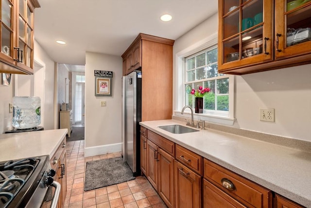 kitchen with appliances with stainless steel finishes, a sink, light countertops, brown cabinets, and recessed lighting
