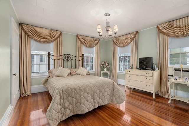 bedroom featuring a chandelier, hardwood / wood-style floors, multiple windows, and baseboards