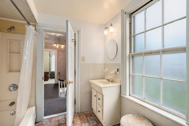 bathroom with shower / bathtub combination with curtain, tile walls, vanity, and a wainscoted wall