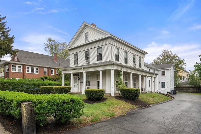 neoclassical / greek revival house featuring a porch and a chimney