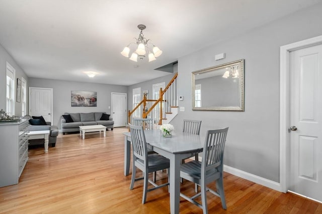 dining space with a chandelier, stairway, light wood finished floors, and baseboards