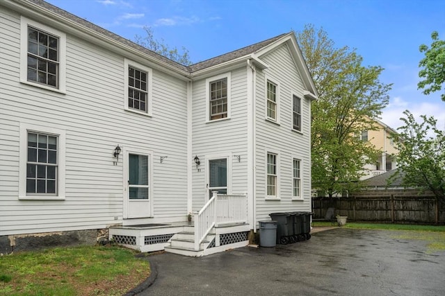 rear view of house with fence and asphalt driveway