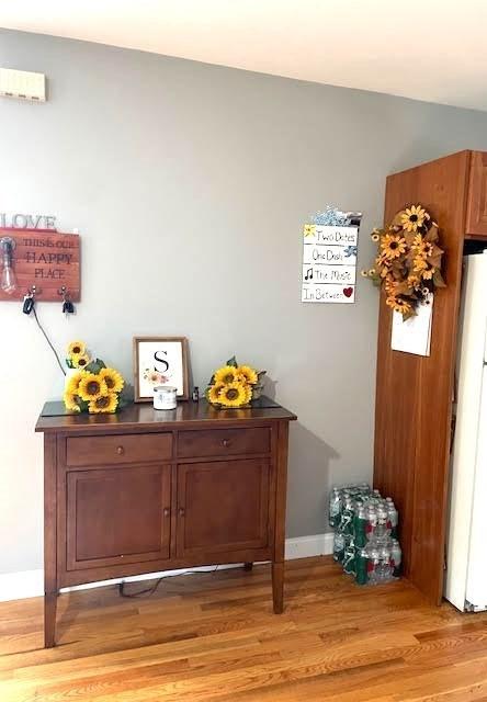 detailed view of freestanding refrigerator, wood finished floors, and baseboards
