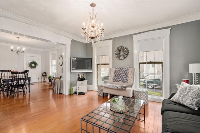 living room featuring a chandelier, light wood-style floors, and ornamental molding