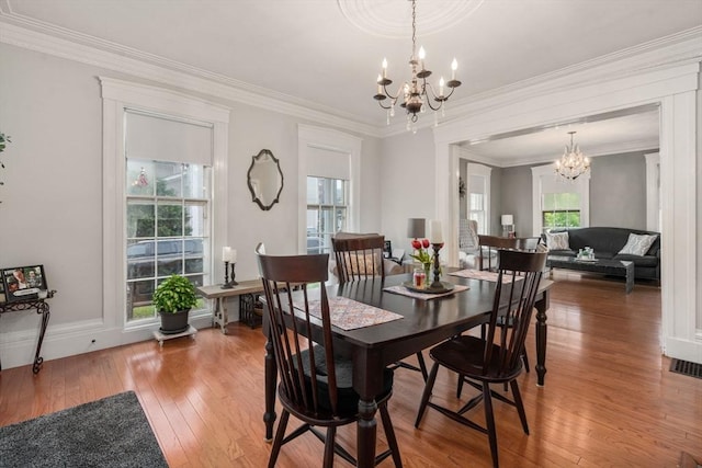 dining room featuring a chandelier, light wood-style floors, crown molding, and baseboards