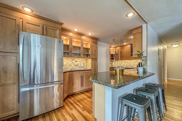 50 Green St Unit 312, Brookline, MA 02446 - kitchen with freestanding refrigerator, light wood-style flooring, a kitchen bar, brown cabinets, and recessed lighting