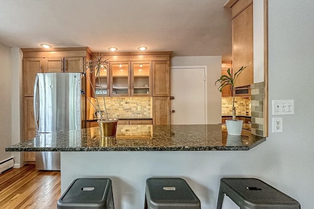 50 Green St Unit 312, Brookline, MA 02446 - kitchen featuring decorative backsplash, a peninsula, a breakfast bar area, freestanding refrigerator, and wood finished floors
