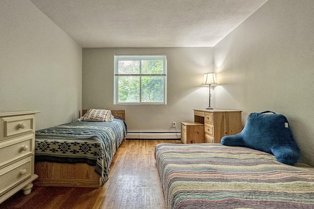 50 Green St Unit 312, Brookline, MA 02446 - bedroom featuring baseboard heating, wood finished floors, and a textured ceiling