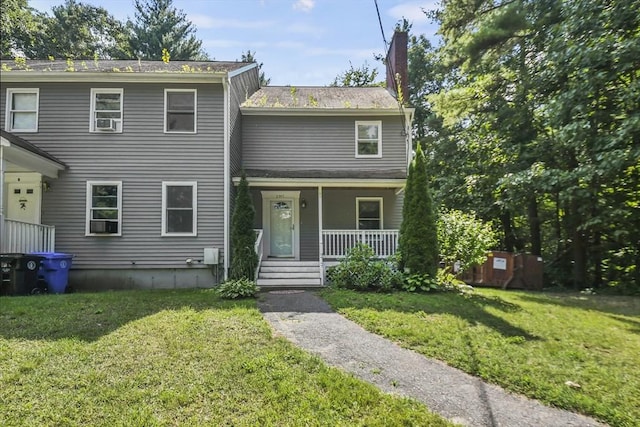 view of front of house with a front lawn, covered porch, and a chimney