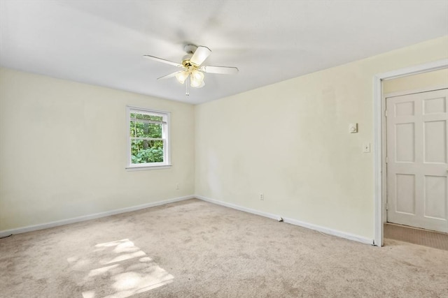 carpeted spare room featuring ceiling fan and baseboards