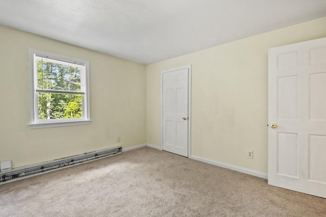 empty room with a baseboard heating unit, carpet floors, and baseboards