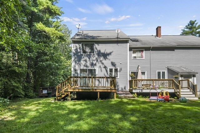 back of property featuring a deck, a lawn, and a chimney