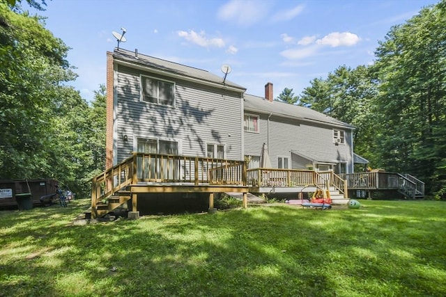 rear view of house featuring a wooden deck, a chimney, and a yard