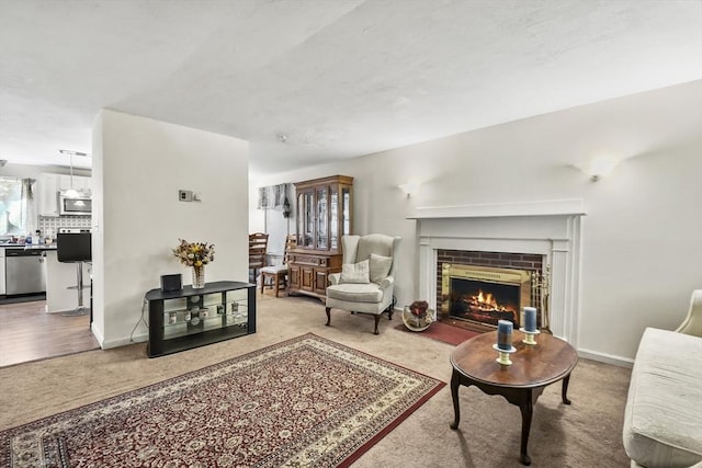 carpeted living area featuring a fireplace and baseboards