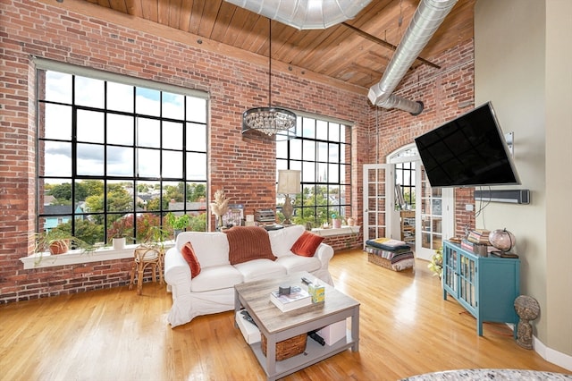 living room featuring wood ceiling, light wood-type flooring, brick wall, and a healthy amount of sunlight