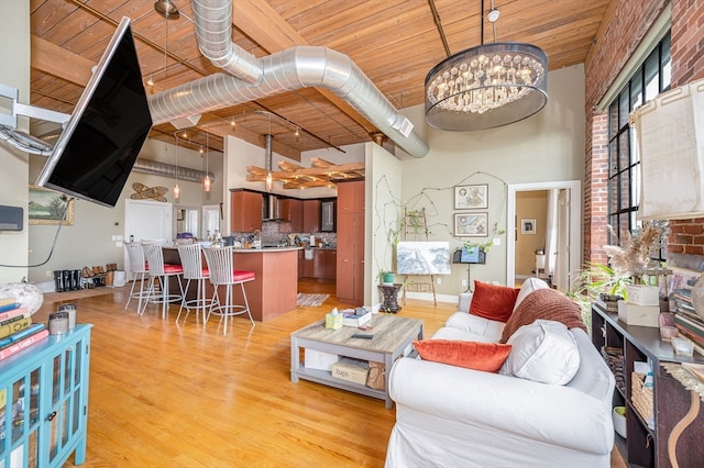 living room with a high ceiling, wood ceiling, light hardwood / wood-style flooring, and a notable chandelier