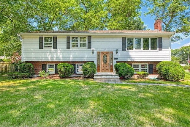 bi-level home with a chimney, a front lawn, and brick siding