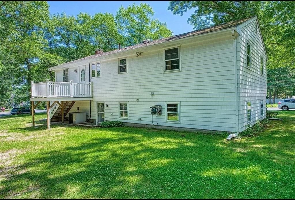 back of house with a deck, cooling unit, a yard, stairway, and a chimney