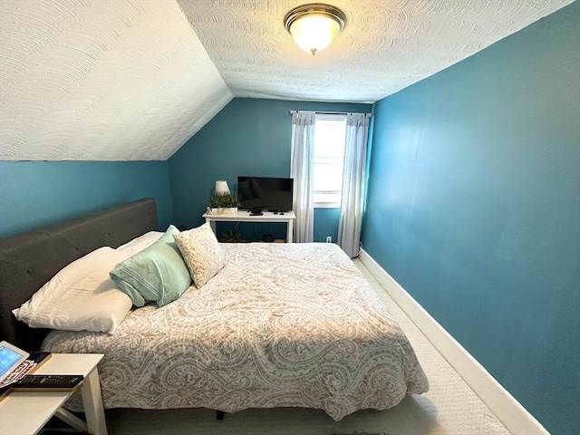 carpeted bedroom featuring lofted ceiling, baseboards, and a textured ceiling