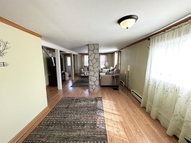 living room with light wood-style flooring, decorative columns, baseboards, and baseboard heating