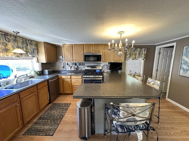 kitchen with a breakfast bar area, an inviting chandelier, a sink, appliances with stainless steel finishes, and dark countertops