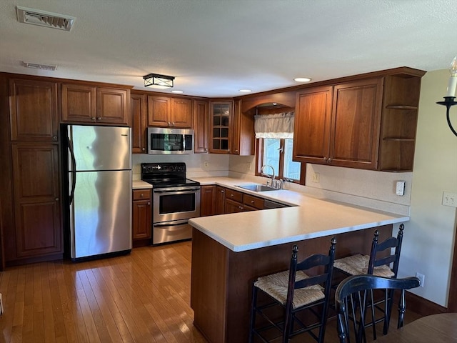 69 Hickory Dr, Raynham, MA 02767 - kitchen featuring appliances with stainless steel finishes, a peninsula, light countertops, a breakfast bar, and open shelves