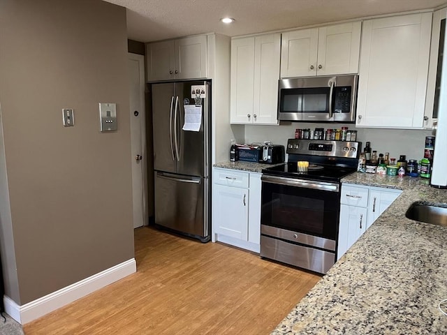 36 Bayview Ter Unit 11, Danvers, MA 01923 - kitchen with appliances with stainless steel finishes, light wood-style floors, white cabinets, light stone counters, and recessed lighting
